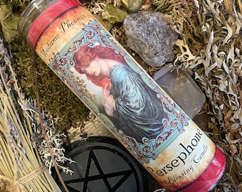 May include: A red and white candle with a vintage illustration of a woman holding an apple. The candle is labelled "Madame Phoenix's Persephone Blessing Candle".