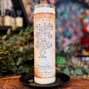 May include: A tall, cylindrical white wax candle in a clear glass container. The label features a vintage-style parchment background with a black ink illustration of an intertwined tree, text reading Madame Phoenix, Money Tree, and Business Growth.