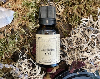 May include: A small brown glass bottle with a black cap, labelled "Madame Phoenix's Confusion Oil - Magical Oil Blend". The bottle is surrounded by dried moss and flowers.