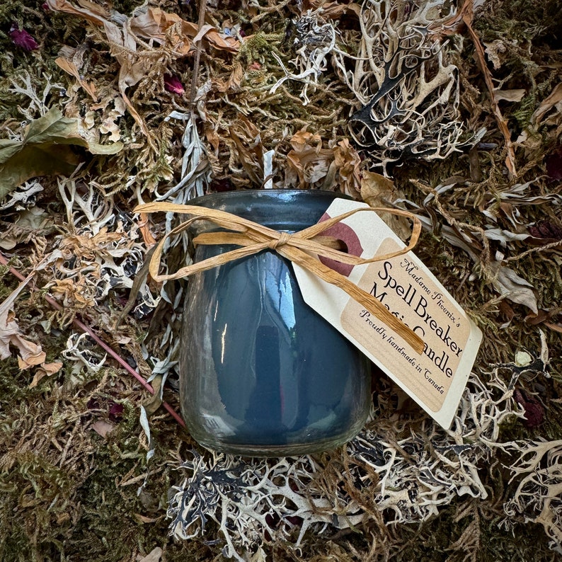 May include: A dark grey Spell Breaker Magic Candle in a glass jar with a brown twine bow and a white tag that reads "Madame Phoenix's Spell Breaker Magic Candle. Proudly handmade in Canada."