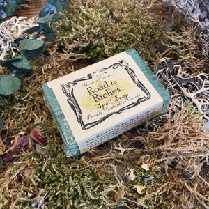 May include: A green and white bar of soap with the text "Madame Pheonix's Road to Riches Spell Soap Proudly Handmade in Canada" and instructions for use.