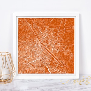 May include: A white line art map of a city printed on a burnt orange background. The map is framed in a white frame.