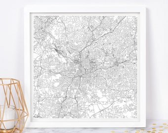 May include: A black and white line art print of a city map. The map is framed in a white frame and is hanging on a white wall.