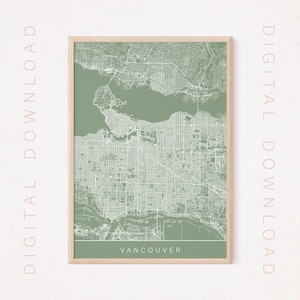 Puede incluir: Un mapa imprimible de Vancouver, Columbia Británica, con un fondo verde salvia y líneas blancas que muestran las calles de la ciudad. El mapa está enmarcado en un marco de madera claro. El texto "Vancouver" está impreso en la parte inferior del mapa.