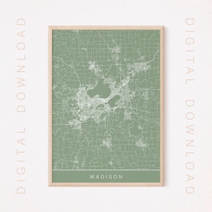Puede incluir: Un mapa imprimible de Madison, Wisconsin, con un fondo verde y líneas blancas que muestran las calles de la ciudad. El mapa está enmarcado en un marco de madera claro. El texto "MADISON" está impreso en la parte inferior del mapa.