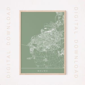 May include: A printable map of Malmo, Sweden, with a green background and white lines showing the city streets. The map is framed in a light wood frame.