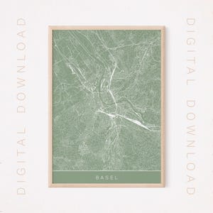 Peut inclure: Une impression encadrée d'une carte de Bâle, en Suisse, de couleur vert clair. La carte présente des contours blancs détaillés des rues et des rivières. Le mot "BASEL" est imprimé en blanc en bas. Le cadre est de couleur bois clair. Les mots "DIGITAL DOWNLOAD" sont imprimés verticalement.
