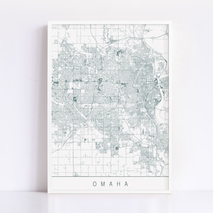 Puede incluir: Un mapa de líneas en blanco y negro de Omaha, Nebraska. El mapa muestra las calles de la ciudad y los principales puntos de referencia. La palabra "OMAHA" está impresa en una fuente simple en la parte inferior del mapa.