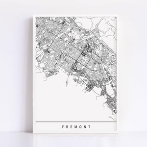 May include: A framed black and white map print of Fremont, California. The detailed map shows streets, buildings, and natural features. The word "FREMONT" is printed in a clean, sans-serif font at the bottom of the print.