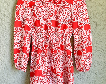 May include: A red and white dress with a floral pattern. The dress has a collared neckline and long sleeves. It has a drawstring waist.