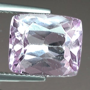 May include: A light pink, faceted gemstone with a rectangular shape. The gemstone is cut and polished, and it has a clear, transparent appearance.