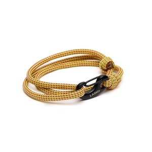 May include: A yellow and red rope bracelet with a black clasp. The clasp is marked with the word "LASKO". The bracelet is made of a woven rope material and is designed to wrap around the wrist.