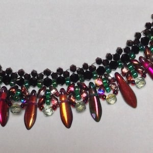 May include: A multi-strand necklace with black beads and dangling teardrop-shaped beads in shades of red, pink, and green.