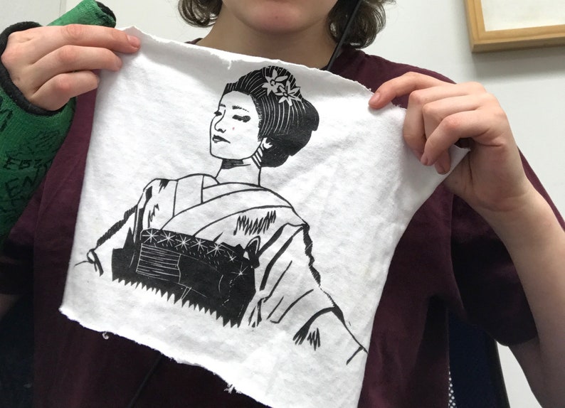 Peut inclure: Une impression en noir et blanc d'une femme en kimono japonais traditionnel. L'impression est sur un tissu blanc avec une texture l&eacute;g&egrave;rement rugueuse.