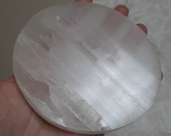 May include: A white selenite charging plate, a circular disc of smooth, white selenite crystal. The plate is about 4 inches in diameter and has a slightly textured surface.