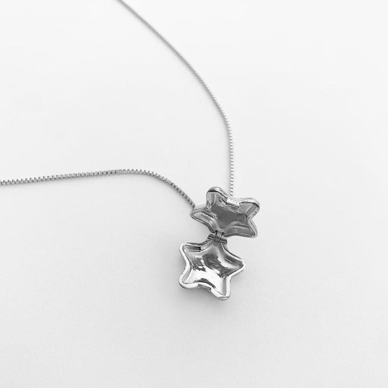Close-up of a star locket necklace inspired by Polly Pocket, featuring a shiny silver charm and a sleek chain.