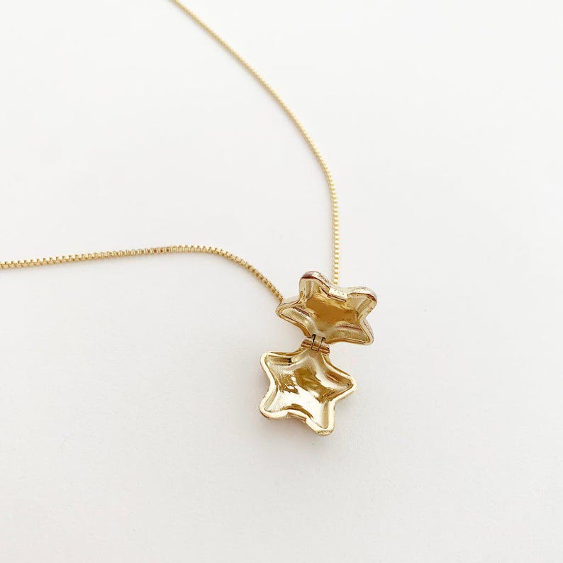 Polly Star Locket Necklace with an open star charm on a gold chain, perfect for layering and styling.