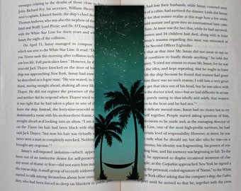 May include: A book with a bookmark featuring a hammock between two palm trees against a starry night sky. The book is open to a page with text about the sinking of the Titanic. The text on the page reads "The World's Most Willing Whipping Boy" and "Shadow of the Titanic".