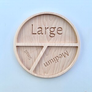 Op de afbeelding: Een houten serveerschaal met drie secties met de labels "Groot", "Medium" en "Klein".