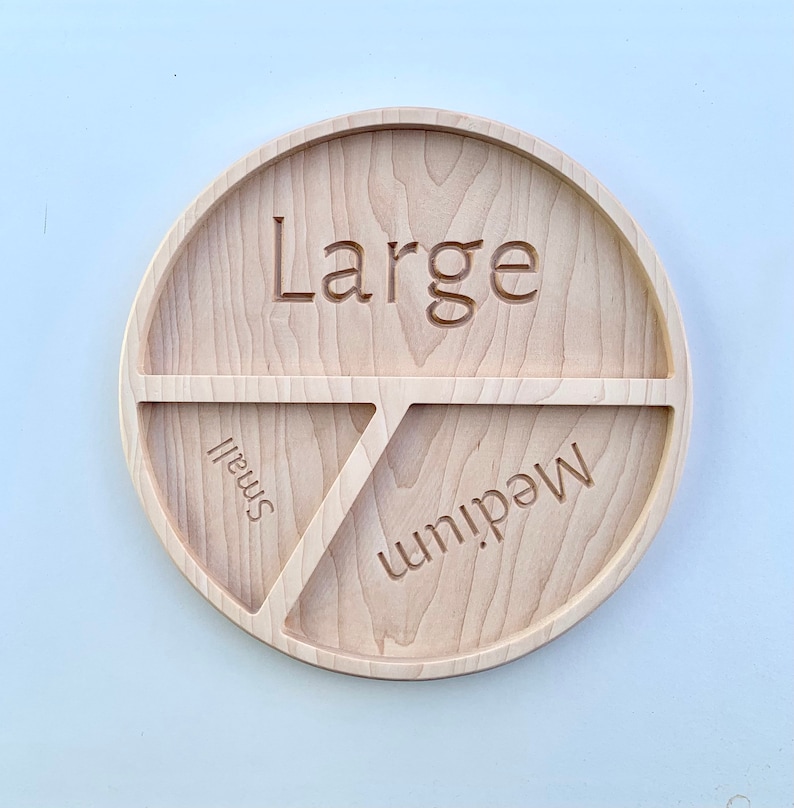 Op de afbeelding: Een houten serveerschaal met drie secties met de labels "Groot", "Medium" en "Klein".