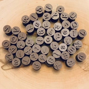 May include: A collection of brown plastic alphabet stamps with a variety of letters and punctuation marks.