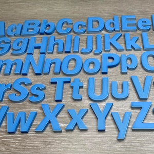 May include: A set of blue plastic letters of the alphabet, arranged in rows, on a woodgrain surface.