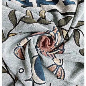 May include: A blue and white patterned throw blanket with a floral design. The blanket is made of a soft, textured fabric and has a subtle sheen.