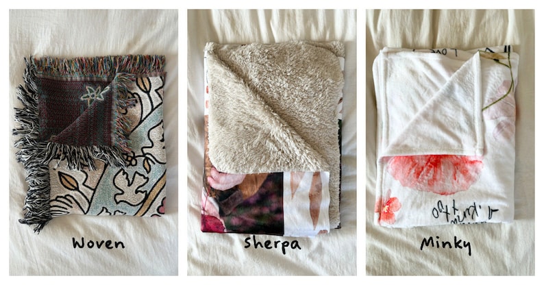 May include: Three folded blankets in different textures: woven, sherpa, and minky. The woven blanket has a colorful floral pattern, the sherpa blanket has a beige fleece texture, and the minky blanket has a white background with a pink floral pattern.