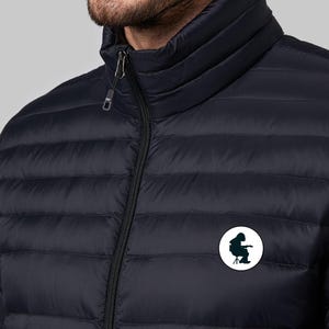 May include: A black quilted jacket with a zipper closure and a small white circle patch on the left chest featuring a silhouette of a person sitting on a chair.