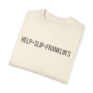 May include: A white t-shirt with the text "HELP>SLIP>FRANKLIN'S" printed in black.