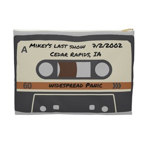 May include: A vintage cassette tape design with the text "Mikey's Last Show 7/2/2002 Cedar Rapids, IA" and "Widespread Panic" printed on it.