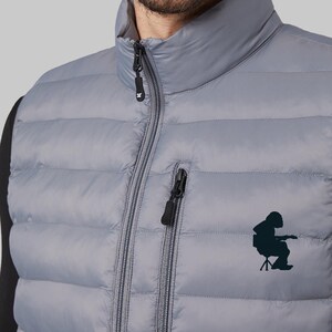 May include: A gray puffer vest with a zipper closure and a black logo on the front. The logo is a silhouette of a person sitting on a chair.