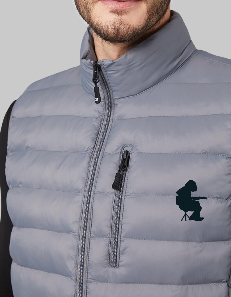 May include: A gray puffer vest with a zipper closure and a black logo on the front. The logo is a silhouette of a person sitting on a chair.