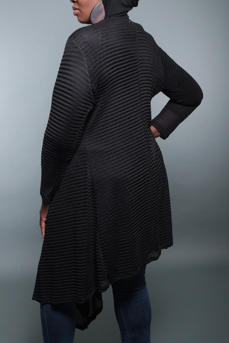 Op de afbeelding: Zwarte lange cardigan met een geribbelde textuur en een high-low zoom. De cardigan is gemaakt van een lichtgewicht, ademende stof.