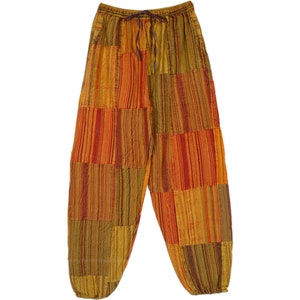 May include: Patchwork pants with a striped pattern in shades of orange, red, and yellow. The pants have an elastic waistband and a drawstring.