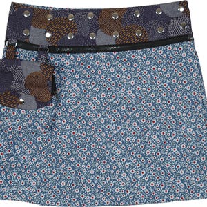 May include: A wrap skirt with a blue floral pattern and a pocket. The skirt features a contrasting waistband with decorative metal rivets and a zipper closure. The pocket has a patchwork design with brown and blue accents.
