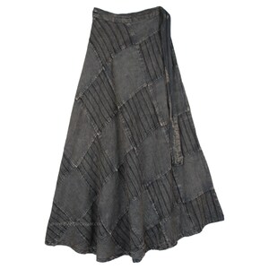 Peut inclure: Une longue jupe grise et fluide avec un motif patchwork. La jupe présente des panneaux rectangulaires cousus ensemble, créant un aspect texturé. Une ceinture en tissu assortie est nouée à la taille. La jupe est faite d'un tissu doux et fluide.