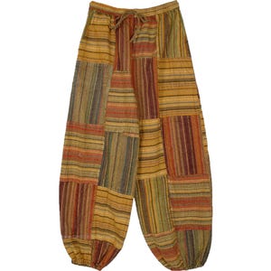 Könnte beinhalten: Patchworkhose mit Kordelzug. Die Hose hat eine Mischung aus vertikalen und horizontalen Streifen in Gelb-, Orange-, Rot- und Grüntönen. Die locker sitzende Hose hat einen gerafften Knöchel.