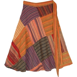 May include: A long, multi-colored wrap skirt with a patchwork design. The skirt is made of various fabrics in shades of orange, red, brown, and purple. The skirt has a long tie that can be wrapped around the waist.