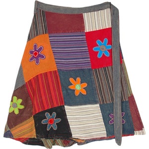 Könnte beinhalten: Ein bunter Patchwork-Wickelrock mit Bindeverschluss. Der Rock besteht aus verschiedenen Stoffen und hat gestickte Blumen in verschiedenen Farben.