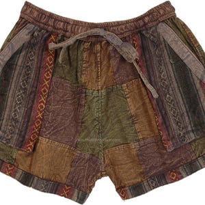 Puede incluir: Pantalones cortos patchwork en tonos tierra de marrón, verde y burdeos. Los pantalones cortos tienen cintura con cordón y una mezcla de paneles de tela estampados y lisos. El diseño incluye patrones geométricos y a rayas.