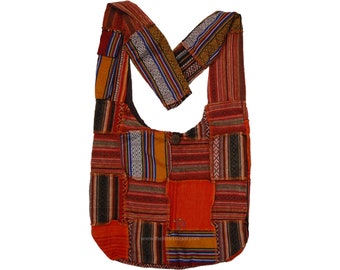 Puede incluir: Bolso de hombro patchwork en tonos rojos, naranjas y marrones. El bolso presenta una variedad de cuadrados de tela estampados, incluyendo rayas y diseños geométricos. La correa tiene un diseño de patchwork similar. Un botón de madera asegura el bolso.