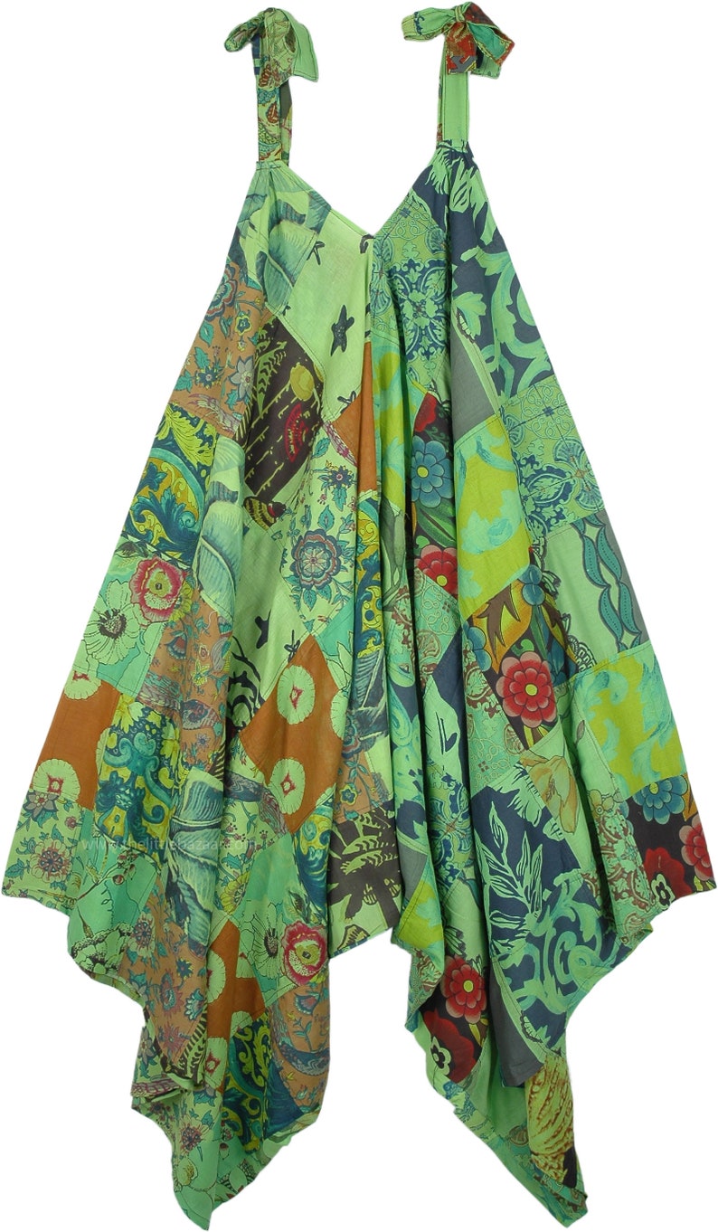 Op de afbeelding: Een groene patchwork jurk met een V-hals en verstelbare bandjes. De jurk is gemaakt van verschillende stoffen met bloemen- en geometrische patronen.