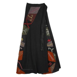 May include: Black wrap skirt with colorful patchwork details. The skirt features embroidered floral and geometric designs in shades of red, green, brown, and orange. A long, black tie secures the wrap closure.