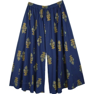 Könnte beinhalten: Weite Palazzo-Hose in tiefem Marineblau mit einem sich wiederholenden goldenen Blattmuster. Die Hose hat einen elastischen Bund und eine fließende Silhouette, geeignet für Freizeitkleidung.