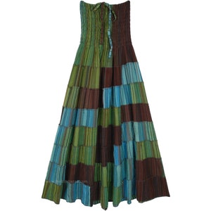 May include: A long, flowing skirt with a patchwork design in shades of green, blue, and brown. The skirt has a gathered waistband and a tiered silhouette.