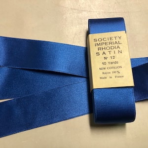 May include: A roll of 10 yards of blue satin ribbon, labeled "Society Imperial Rhodia Satin N° 12 New Cotillon Rayon 100% Made in France".