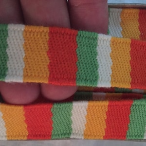 May include: Two pieces of striped elastic with alternating bands of green, white, orange, and red.