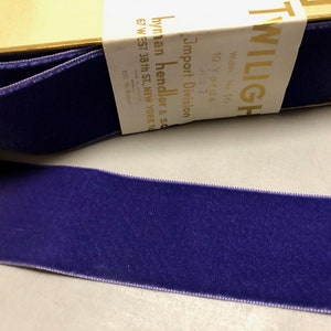 以下が含まれることがあります： 幅1/16インチの紫色のベルベットリボン10ヤードロール。ラベルには「TWILIGHT」と「Import Division Hyman Hendler & Sons 67 W. 38th St. New York 18 100% Rayon」と記載されています。