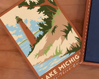 May include: A vintage-style postcard magnet featuring a lighthouse on a sandy beach with blue water and green trees. The text on the magnet reads "Lake Michigan - The Third Coast."